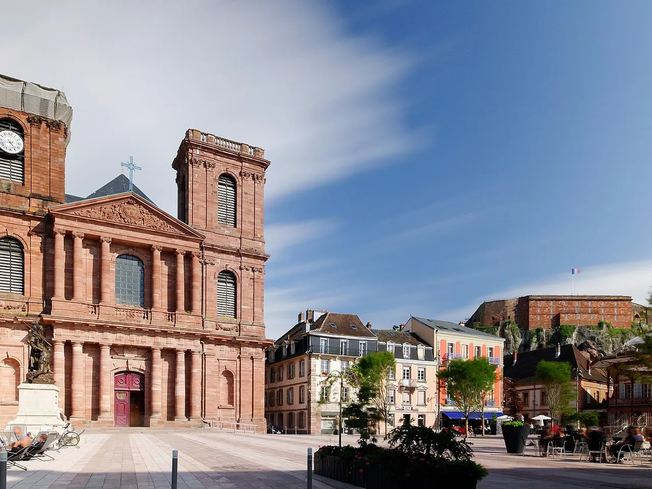 Place d’Armes de Belfort avec la façade en grès rouge de la cathédrale Saint-Christophe et, au loin, la citadelle sur son rocher