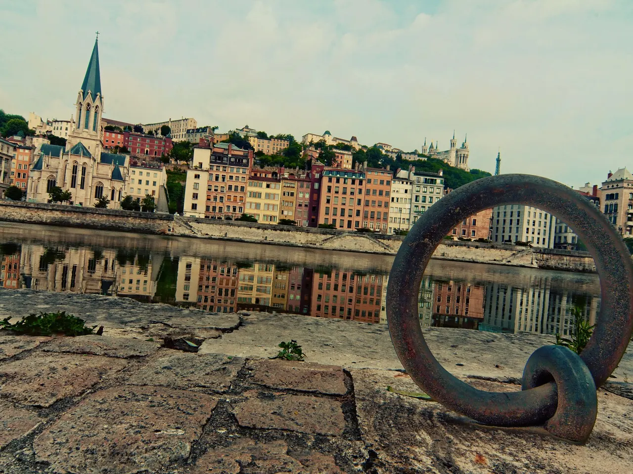 Anneau d’amarrage sur un quai de la Saône, face à l’église Saint-Georges, aux façades colorées du Vieux-Lyon et à Fourvière.